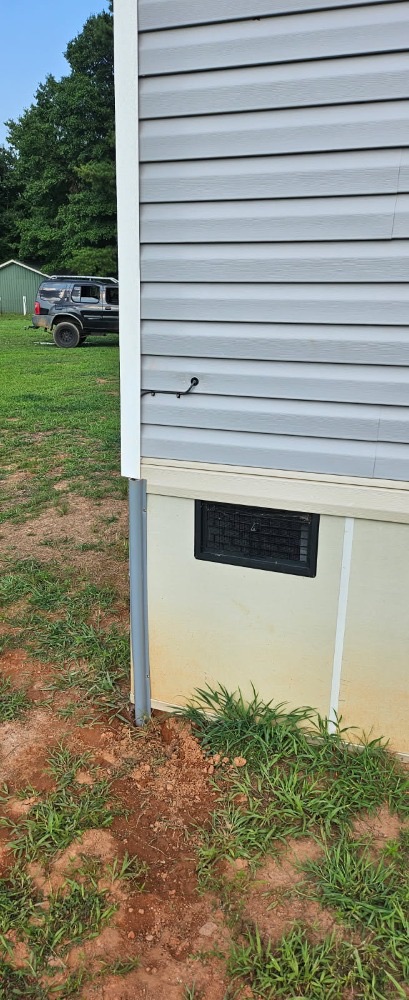 Cable run routed down exterior siding in conduit and sealed at the crawl-space entry